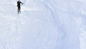 Ski Alpinist Traversing Snow Scarp