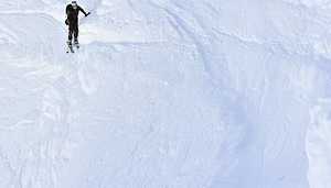 Ski Alpinist Traversing Snow Scarp